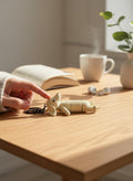 a sleepy beige sausage dog flexi key chain laying on its back on a wooden desk